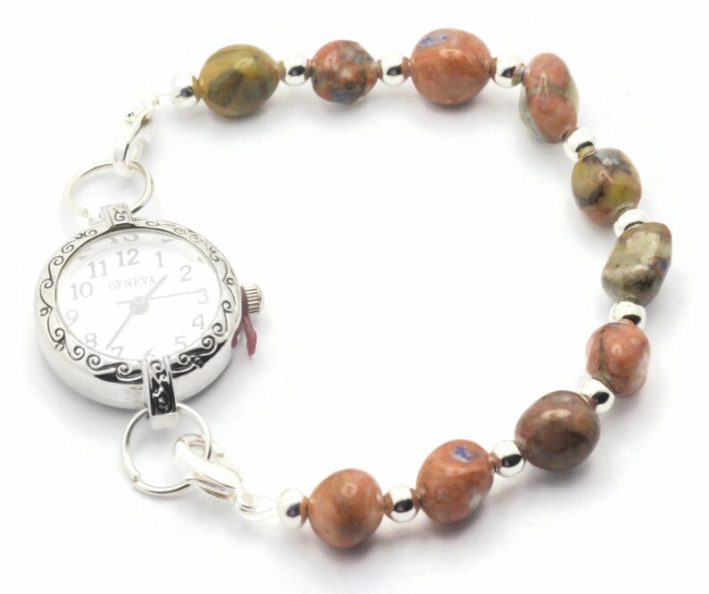 May include: A silver watch with a white face and black numbers is attached to a bracelet made of brown, green, and white stones.