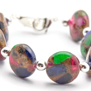 May include: A bracelet made of round, multi-colored glass beads with gold flecks. The beads are a mix of green, blue, red, and brown.