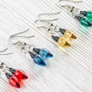 Op de afbeelding: Vier paar hangende oorbellen met lampvormige bedels. De bedels zijn rood, blauw, geel en groen.
