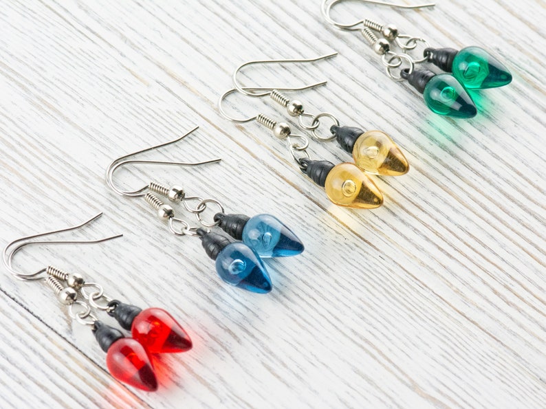 Op de afbeelding: Vier paar hangende oorbellen met lampvormige bedels. De bedels zijn rood, blauw, geel en groen.