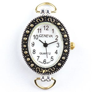May include: Oval Geneva quartz watch with a white face, black hands, and gold-tone accents. The watch has a black and gold bezel and gold-tone loops for attachment. The watch face displays the word "GENEVA" and "QUARTZ".