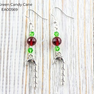 Pode incluir: Um par de brincos com tema natalino. Cada brinco apresenta um pingente de bengala doce prateada, contas vermelhas e verdes e um gancho prateado. O texto "Red & Green Candy Cane EA00569" &eacute; vis&iacute;vel na imagem.