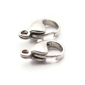 May include: Two silver-toned lobster clasps for jewelry making. The clasps are made of metal and have a polished finish.