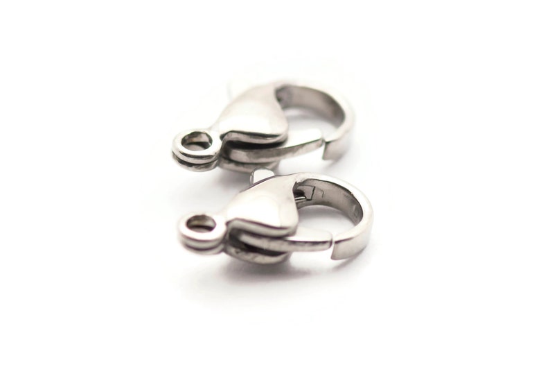 May include: Two silver-toned lobster clasps for jewelry making. The clasps are made of metal and have a polished finish.