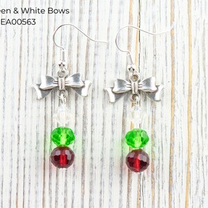Pode incluir: Brincos de la&ccedil;o prateados com contas vermelhas, verdes e transparentes. Os brincos apresentam um design de la&ccedil;o na parte superior, com contas vermelhas, verdes e transparentes penduradas abaixo. O texto "Red, Green & White Bows" est&aacute; na imagem.