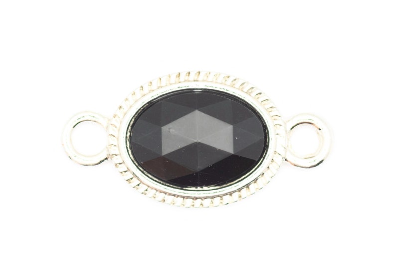 May include: A silver oval connector with a black faceted gemstone. The connector has two loops on either side for attaching jewelry.