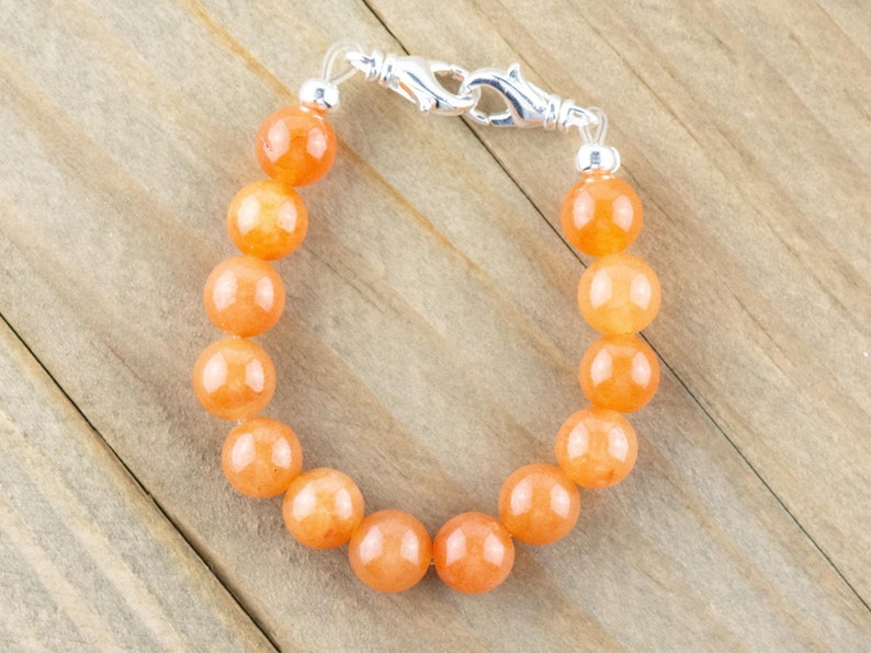 Op de afbeelding: Een armband gemaakt van oranje edelsteen kralen met een zilveren sluiting.