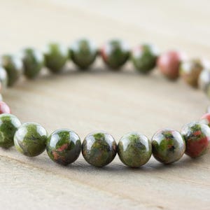 May include: A green and red gemstone bracelet with round beads. The bracelet is made of natural stones and is a popular choice for those who enjoy wearing jewelry with a natural look.