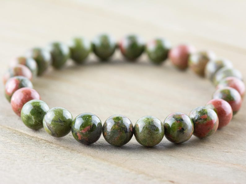 May include: A green and red gemstone bracelet with round beads. The bracelet is made of natural stones and is a popular choice for those who enjoy wearing jewelry with a natural look.