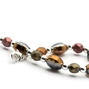 K&ouml;nnte beinhalten: Ein Armband mit silbernem Verschluss und braunen, goldenen und klaren Glasperlen.