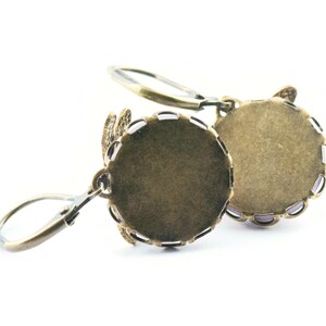 Pode incluir: Um par de engastes para brincos de cor bronze com um design de filigrana decorativo. Os engastes s&atilde;o redondos e t&ecirc;m um acabamento liso e polido.