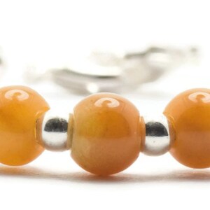 May include: A bracelet made of orange gemstone beads and silver spacer beads.