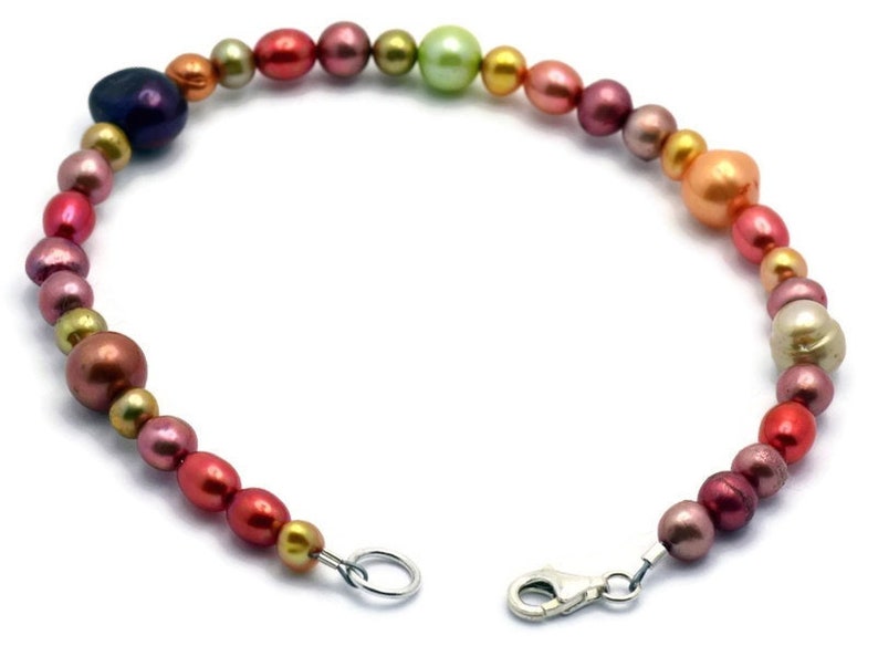 Pu&ograve; includere: Un braccialetto di perle multicolori con una chiusura argentata. Le perle sono in tonalit&agrave; di rosa, arancio, verde e oro.