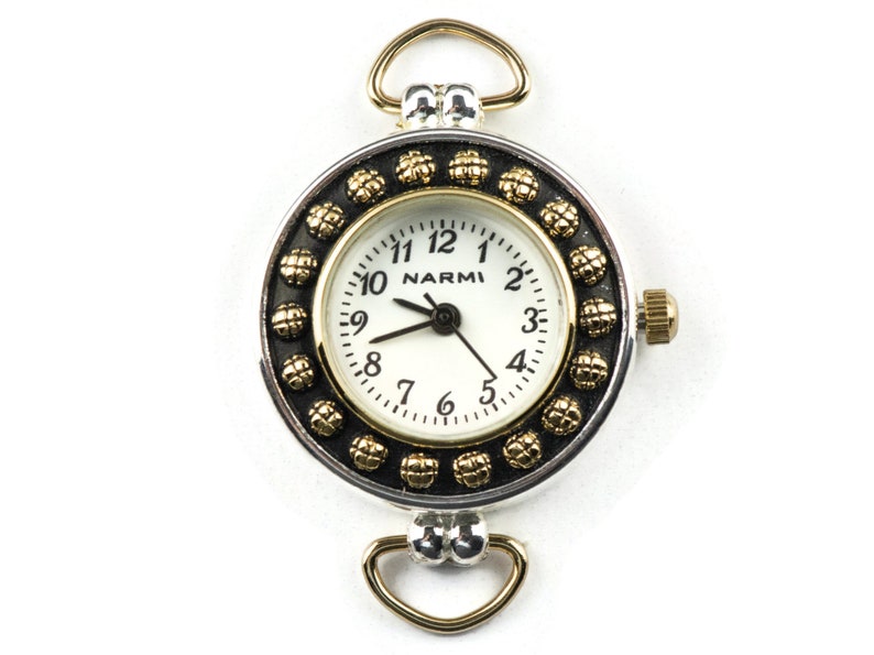 May include: A silver and gold tone watch with a white face and black numbers. The watch has a decorative bezel with gold accents and a loop for attaching to a chain.