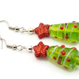 Op de afbeelding: Een paar groene glazen kerstboom oorbellen met rode glittersterren en zilveren haakjes.