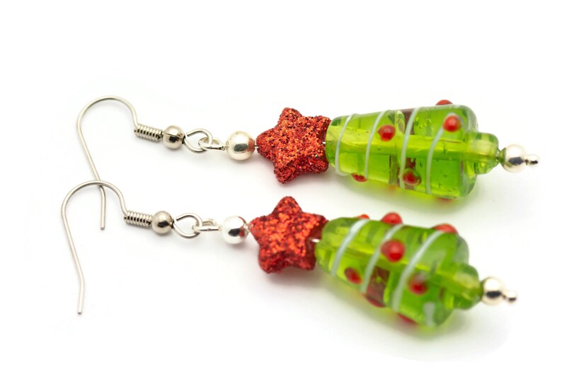Op de afbeelding: Een paar groene glazen kerstboom oorbellen met rode glittersterren en zilveren haakjes.