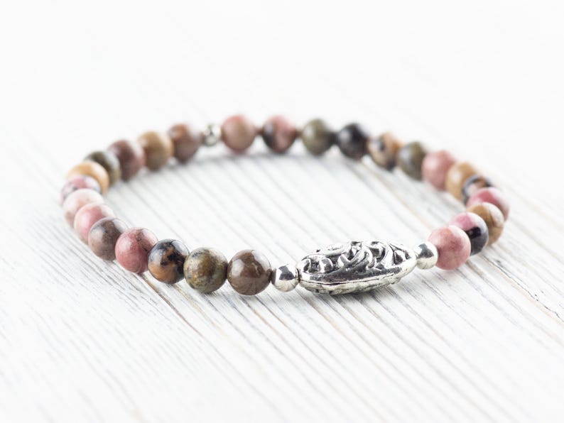 Puede incluir: Un brazalete de piedras preciosas rosa, marr&oacute;n y verde con un cierre plateado. El brazalete est&aacute; hecho de peque&ntilde;as cuentas redondas.