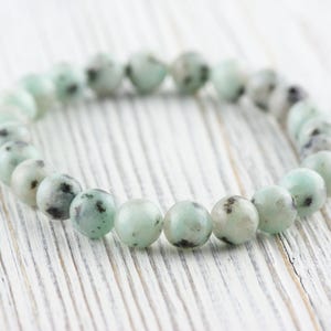 Puede incluir: Un brazalete hecho de cuentas verdes y negras moteadas. El brazalete est&aacute; hecho de piedra natural y tiene aproximadamente 18 cm de largo.