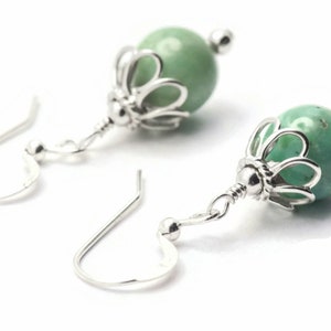 Puede incluir: Un par de pendientes de plata con cuentas de piedras preciosas verdes y un delicado dise&ntilde;o floral.