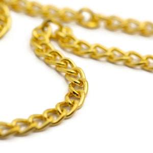 Puede incluir: Primer plano de un collar de cadena de oro. La cadena est&aacute; hecha de eslabones gruesos e interconectados.