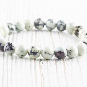 May include: A white and black speckled stone bracelet with round beads.