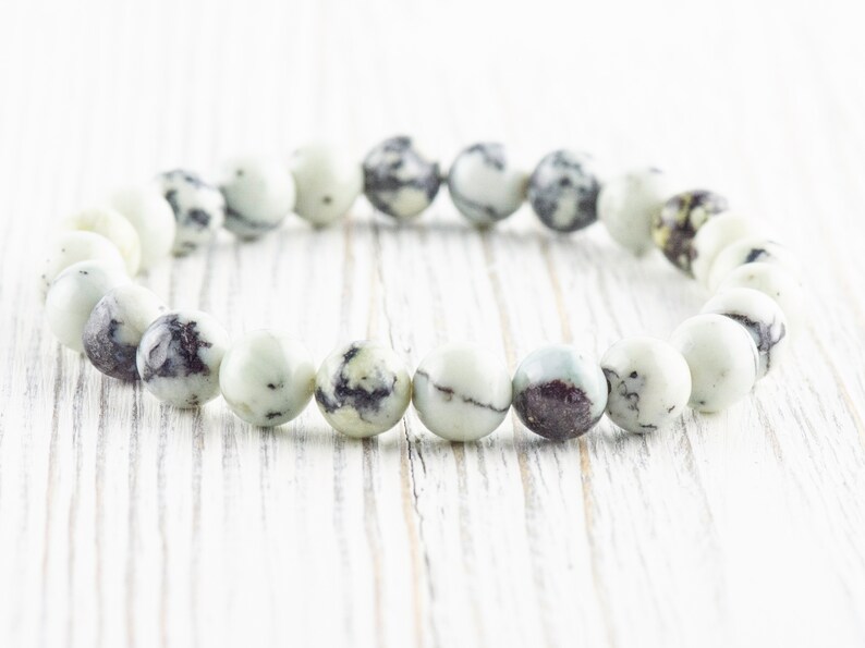 May include: A white and black speckled stone bracelet with round beads.