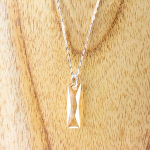 May include: A silver chain necklace with a clear, faceted, rectangular pendant.
