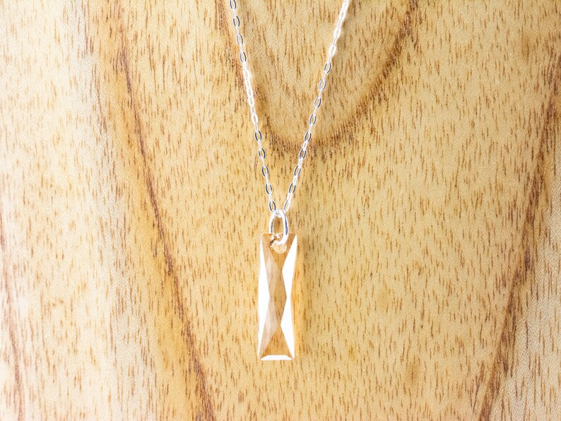 May include: A silver chain necklace with a clear, faceted, rectangular pendant.
