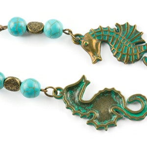 May include: A pair of earrings featuring turquoise beads and bronze seahorse charms. The seahorses have a green patina finish.