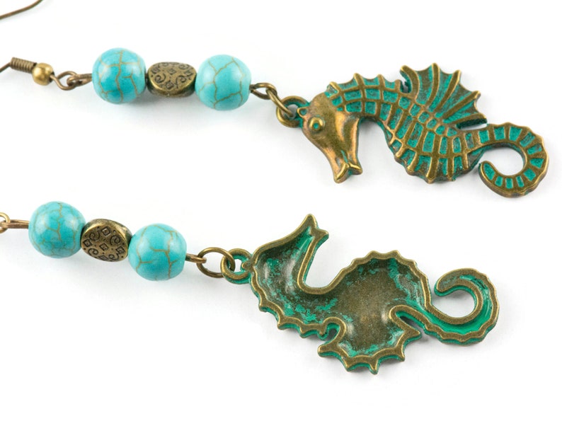 May include: A pair of earrings featuring turquoise beads and bronze seahorse charms. The seahorses have a green patina finish.