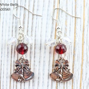 Pode incluir: Brincos pendurados prateados com uma conta facetada vermelha e contas de cristal transparentes. Cada brinco tem um pingente em forma de dois sinos com um la&ccedil;o. O texto "Red & White Bells EA00561" est&aacute; no canto superior esquerdo.