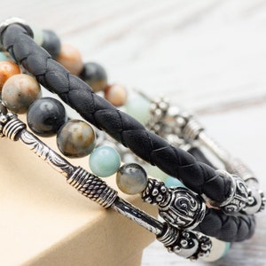 May include: A black leather bracelet with silver accents and multi-colored gemstone beads.