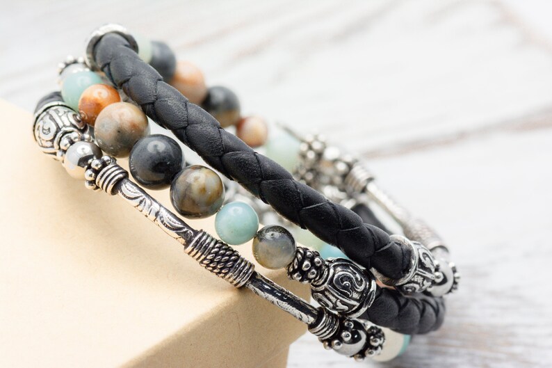 May include: A black leather bracelet with silver accents and multi-colored gemstone beads.