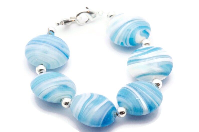 May include: A bracelet made of blue and white swirled glass beads with silver accents.