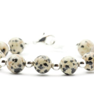 May include: A bracelet made of white and black dalmatian jasper beads with silver accents.