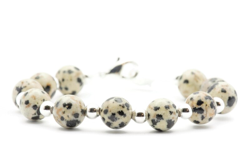 May include: A bracelet made of white and black dalmatian jasper beads with silver accents.