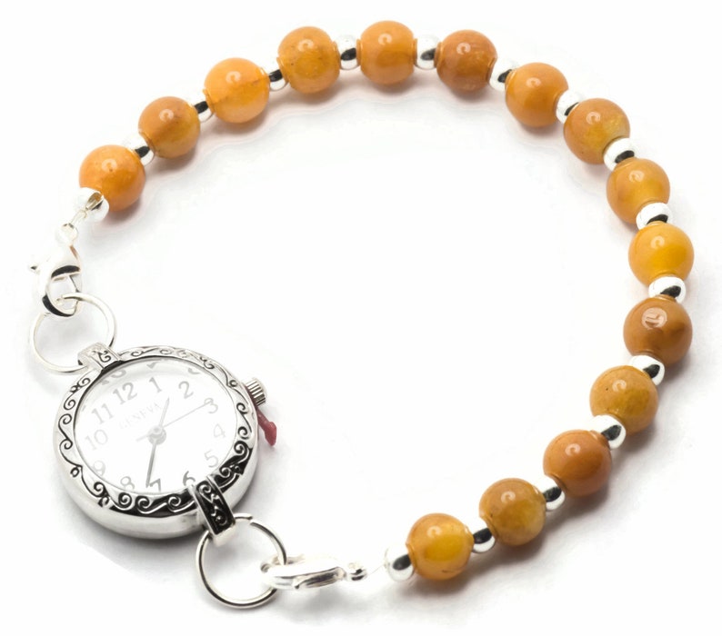 May include: A silver watch with a white face and black numbers is attached to a bracelet made of amber-coloured beads and silver spacers.