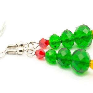 May include: A pair of green crystal Christmas tree earrings with red and orange accents. The earrings are made with faceted beads and have silver hooks.