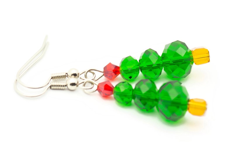 May include: A pair of green crystal Christmas tree earrings with red and orange accents. The earrings are made with faceted beads and have silver hooks.