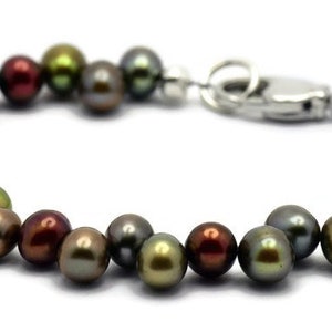 Puede incluir: Un brazalete hecho de perlas de color verde oscuro, marr&oacute;n y negro con un cierre plateado.