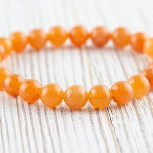 May include: A bracelet made of orange carnelian beads. The beads are round and smooth, and the bracelet is strung on elastic.