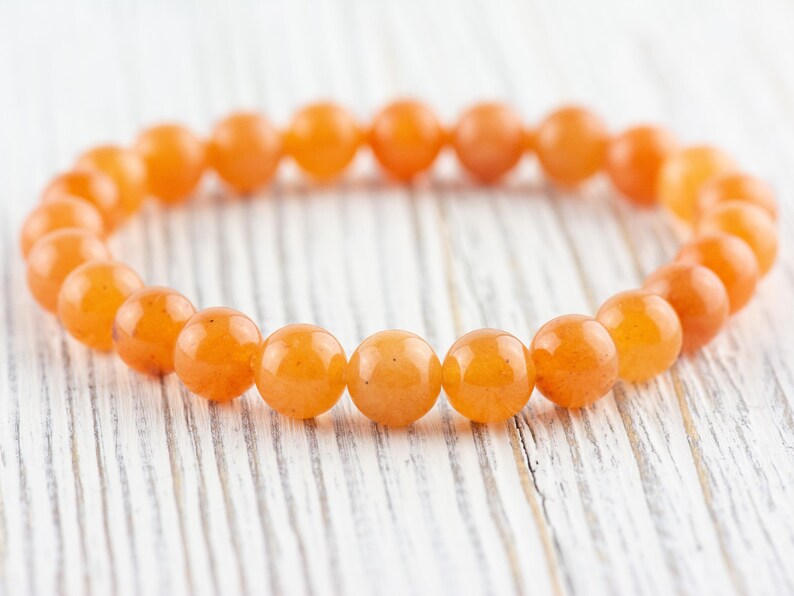 May include: A bracelet made of orange carnelian beads. The beads are round and smooth, and the bracelet is strung on elastic.