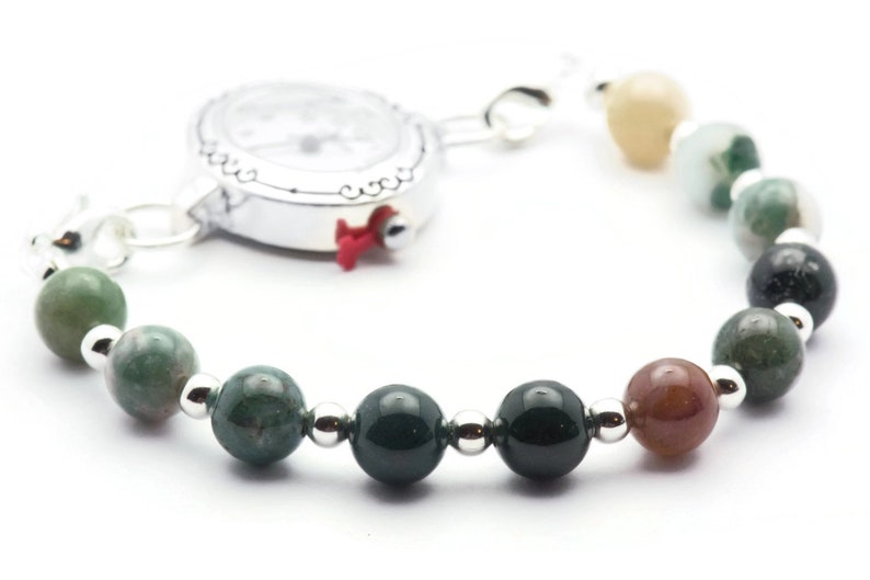 Pode incluir: Um rel&oacute;gio prateado com um mostrador branco e uma pulseira de contas de &aacute;gata verde. A pulseira tem contas prateadas entre cada conta de &aacute;gata.