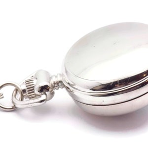 May include: A silver pocket watch with a chain attached. The watch has a round face and a hinged lid.