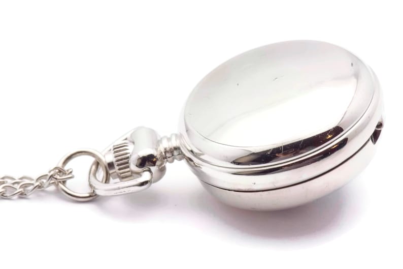 May include: A silver pocket watch with a chain attached. The watch has a round face and a hinged lid.