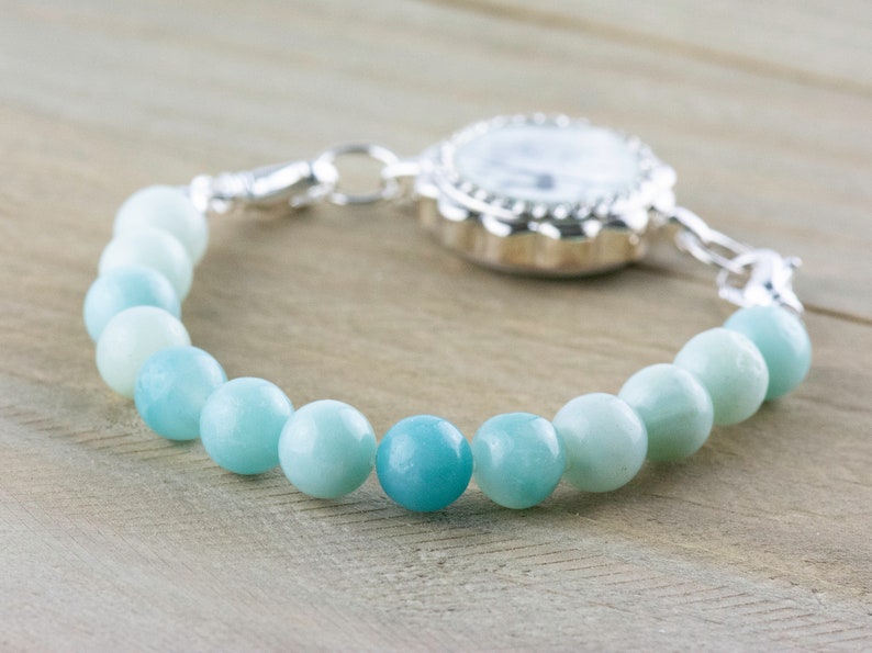 May include: A silver watch with a blue and green gemstone beaded bracelet.