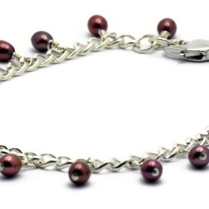 May include: A silver chain bracelet with a lobster clasp and dangling burgundy pearls.