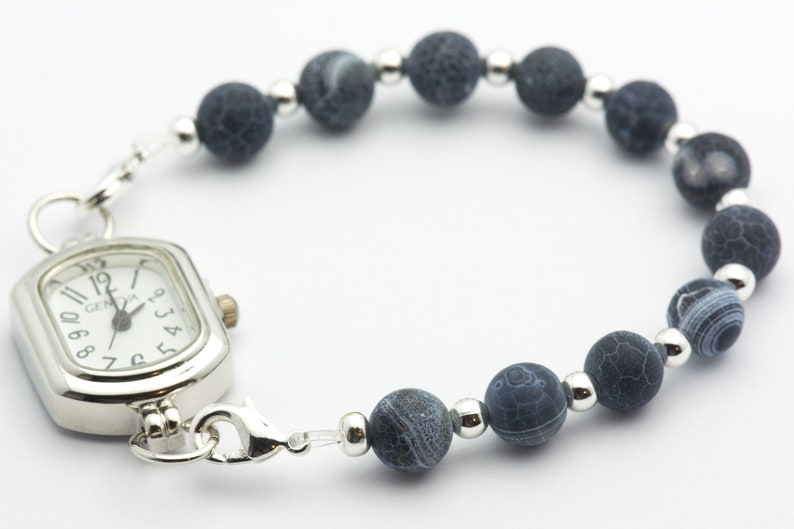 May include: A silver watch with a square face and black agate beads on a silver chain.