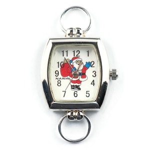 May include: A silver pocket watch with a white face and a Santa Claus design. The watch has a square face with rounded corners and a silver chain.