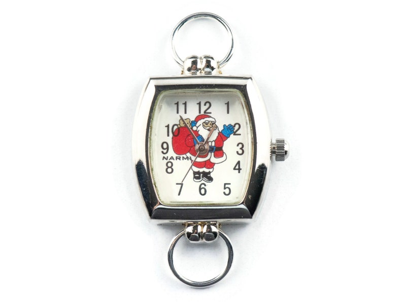 May include: A silver pocket watch with a white face and a Santa Claus design. The watch has a square face with rounded corners and a silver chain.